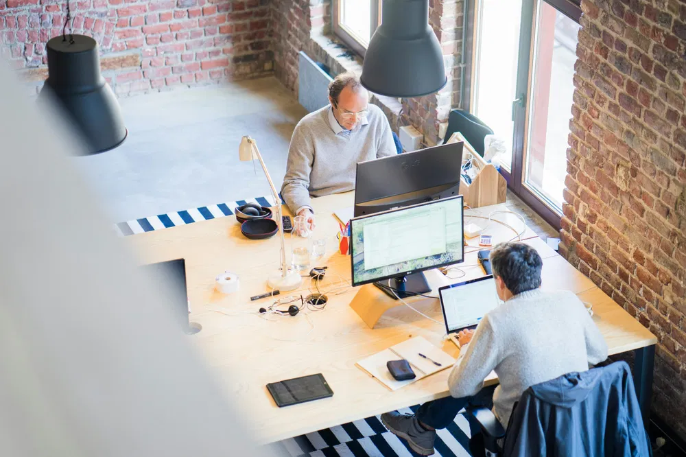 Two persons sitting at their desk in an open space
